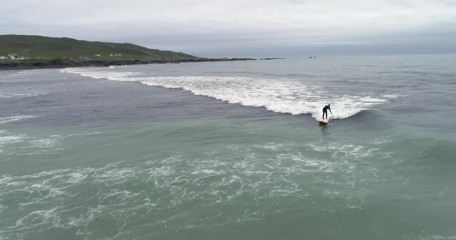 Someone is surfing and paddling their board in the ocean