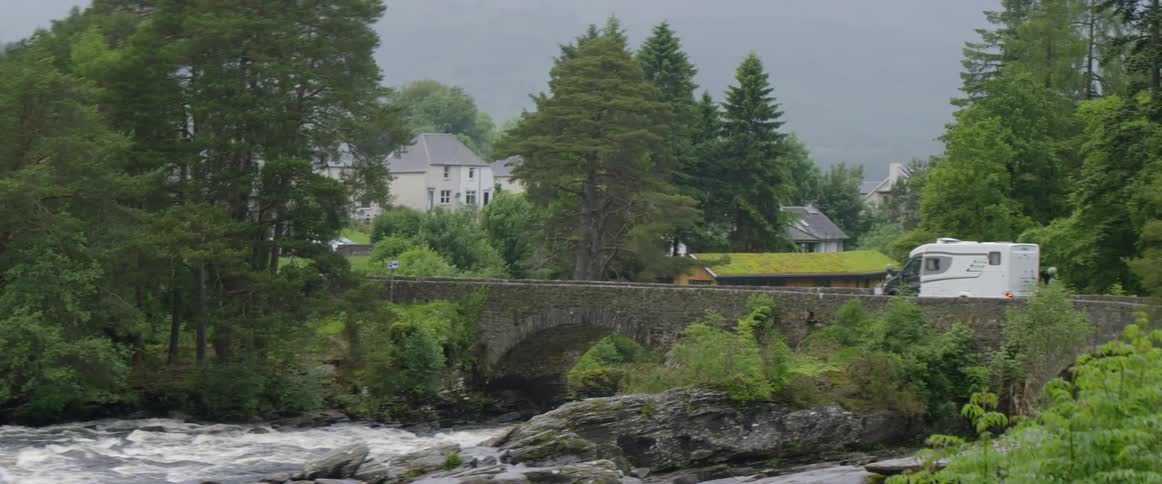 A van driving across a stone bridge