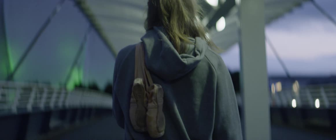 A woman with a purse around her shoulder walks under a structure