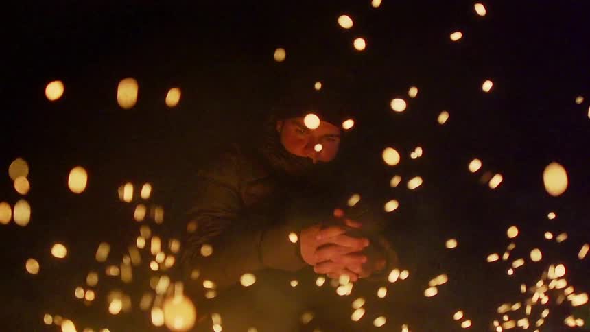 Man warms his hands over a fire outside