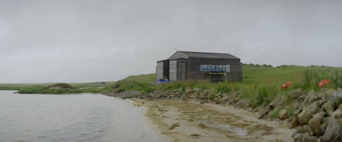 Water flows towards a shed on the shore