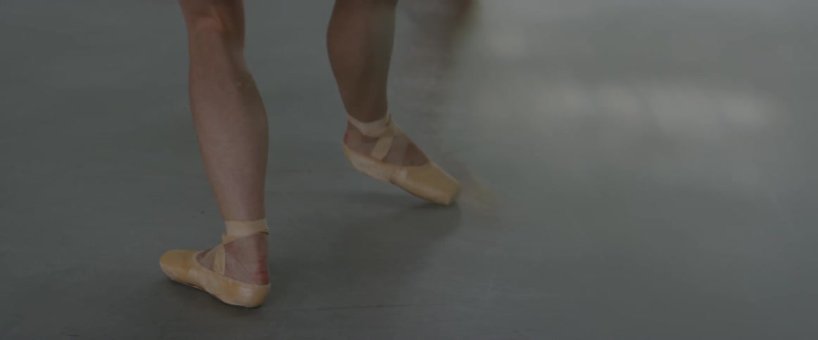 A girl is wearing ballet shoes and is practicing