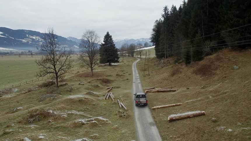 A truck is traveling down a small dirt road