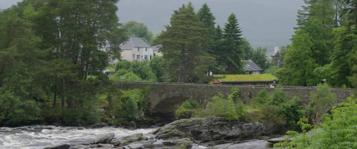 Water flows down a stream under a bridge