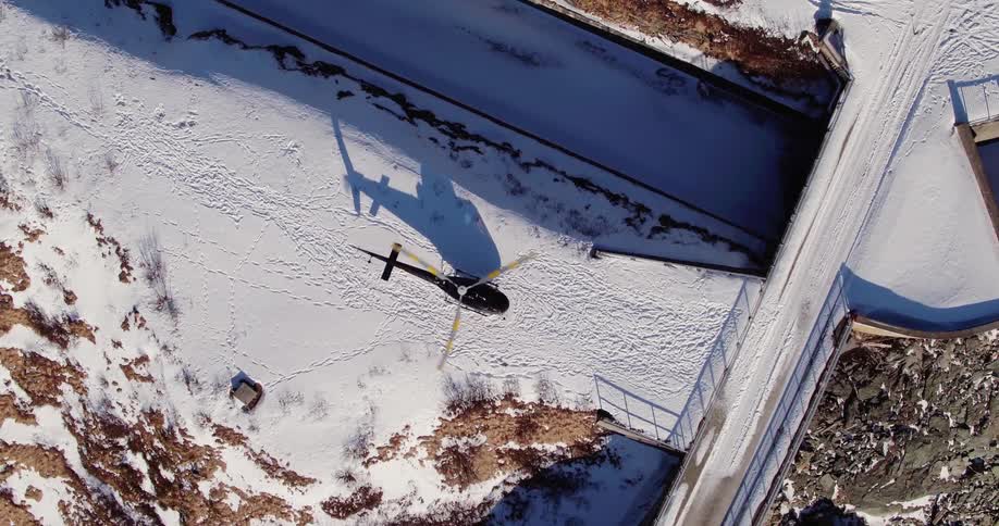 The blades of a helicopter parked on snow rotate