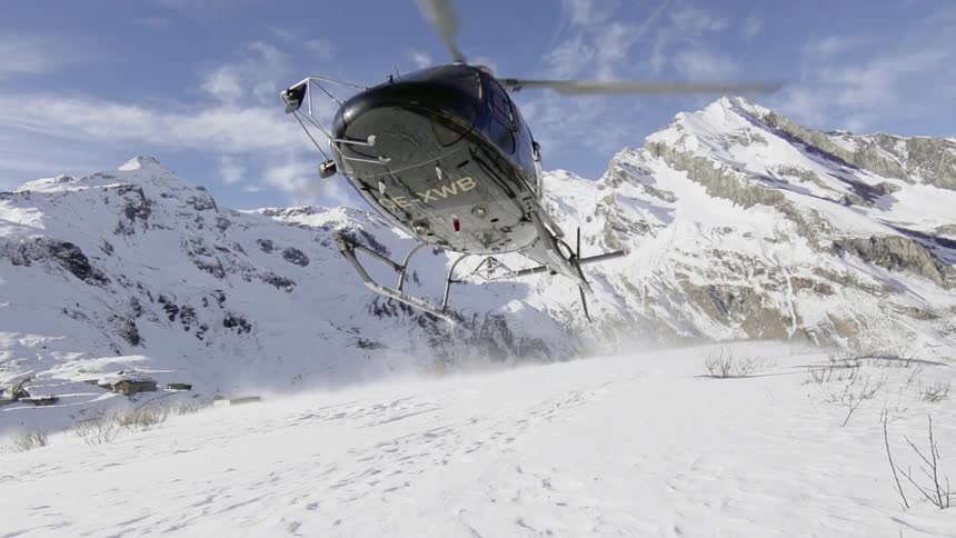 A helicopter takes off from a snow covered mountain