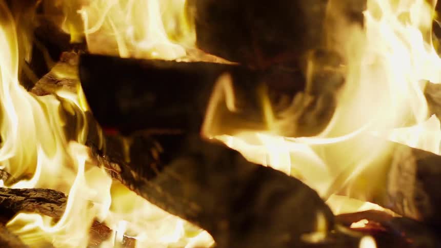 A fire burns outside at night