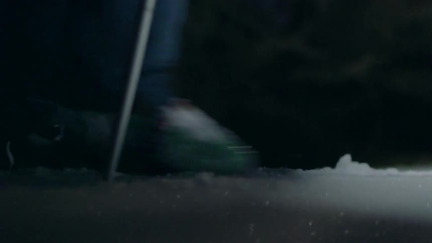 Someone is wearing skies and is travelling across a snowy landscape at night