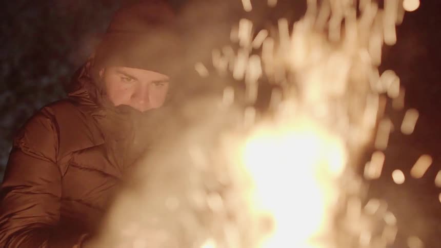 People are sitting around a fire as it sparks