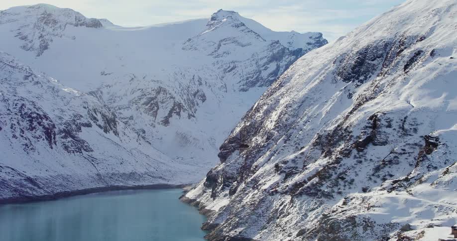 A helicopter flies between mountains over a valley
