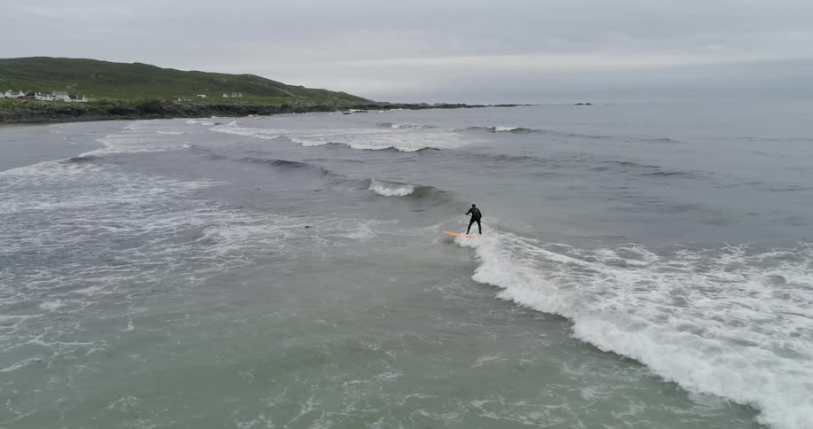 A man is surfing near the shore on a cloudy day