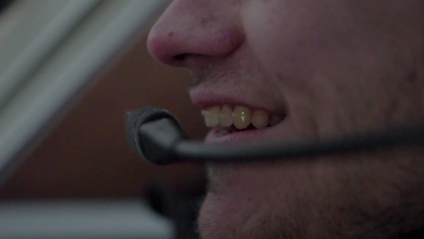A man smiles while talking into a microphone