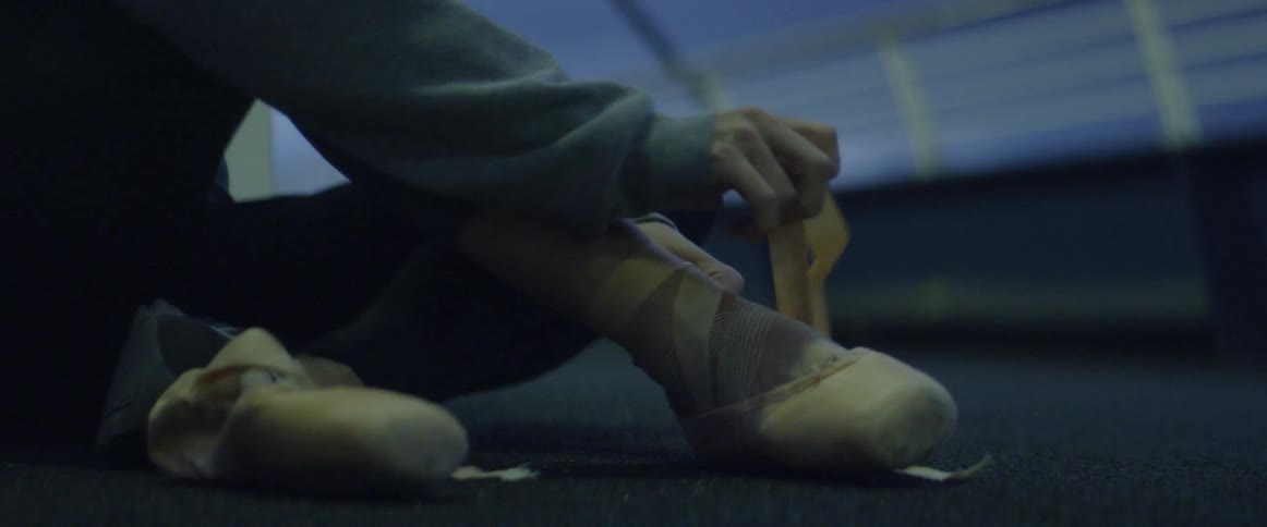 A dancer is strapping on their shoes
