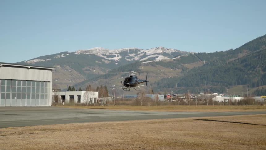 A black helicopter slowly takes off