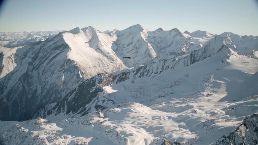 A helicopter flies above mountains