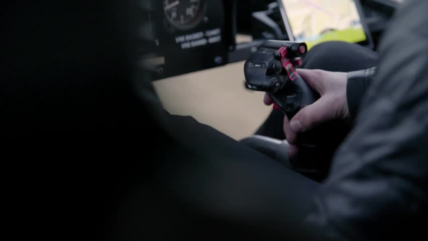 A pilot is operating the controls of a helicopter during the day