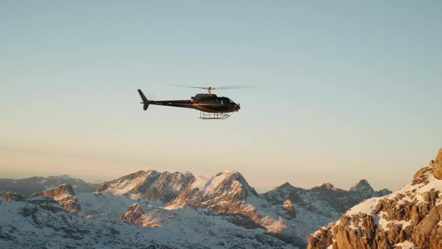 A helicopter flies above mountains