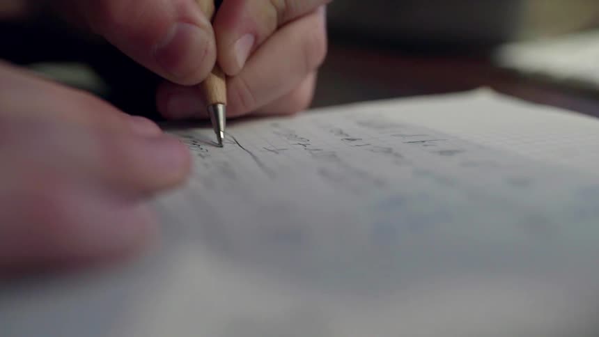 Person writes on a piece of paper with a pen