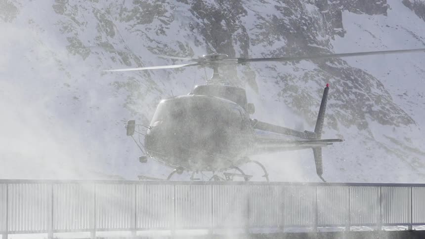 A helicopter is hovering over a snowy lake