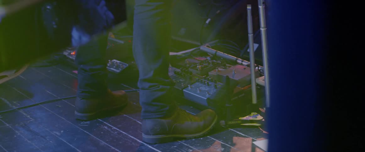 A man taps his boots by the machine on stage