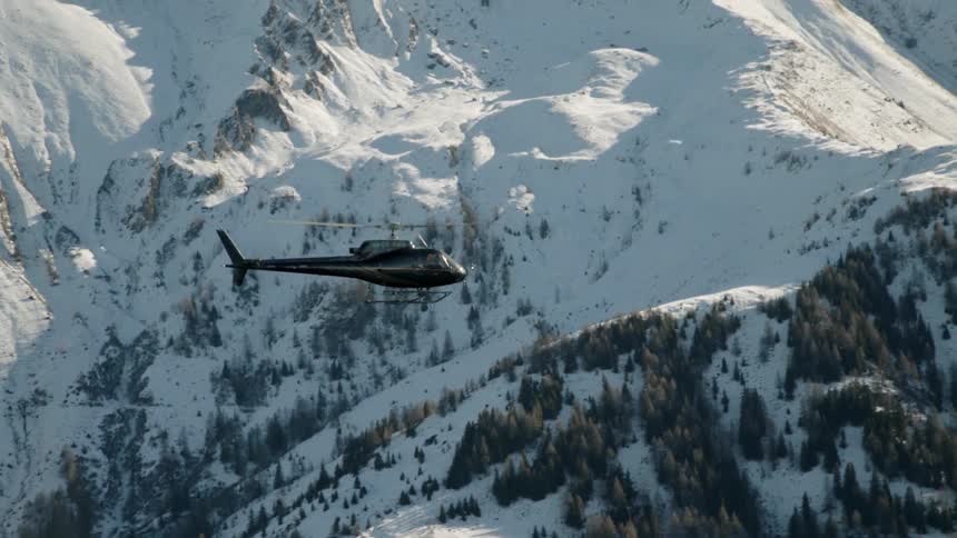Helicopter flies over snowy mountains