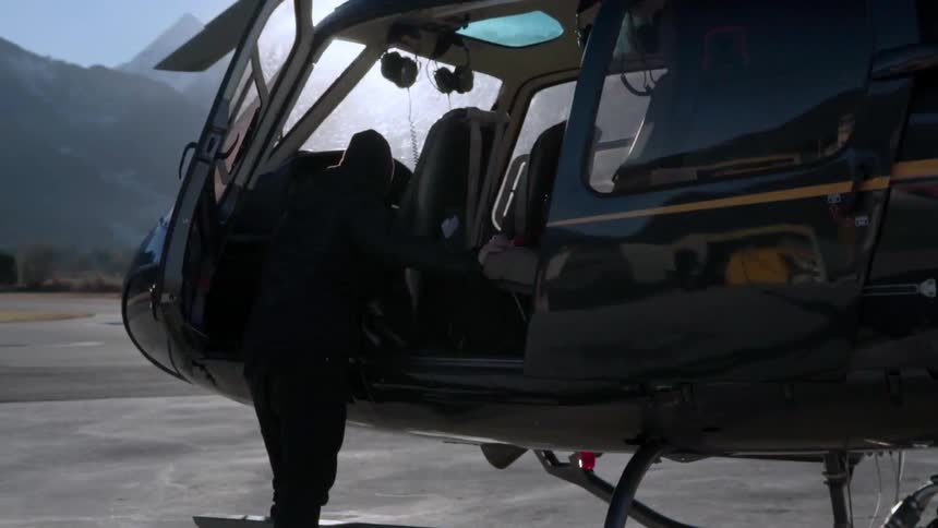 A man leans into the open door of a helicopter