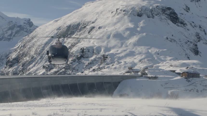 A helicopter flies in snowy mountains
