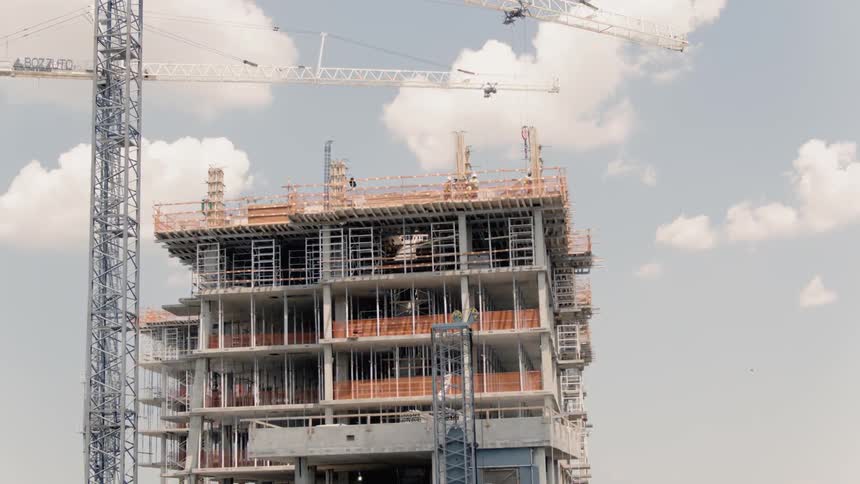 Cranes operate at a construction site on a cloudy day