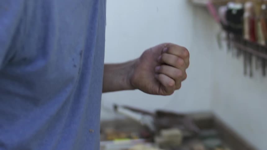 A man is hammering some wood and hits his thumb by mistake