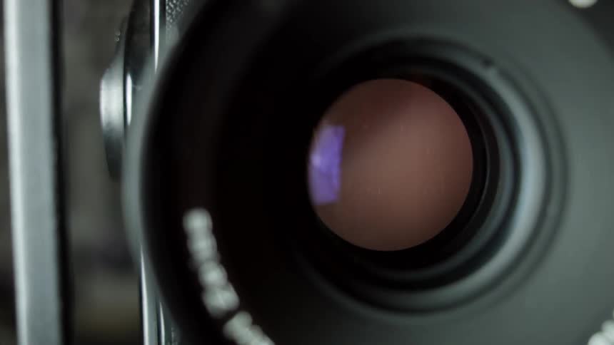 Light flashes through a lens of a analog camera aperture