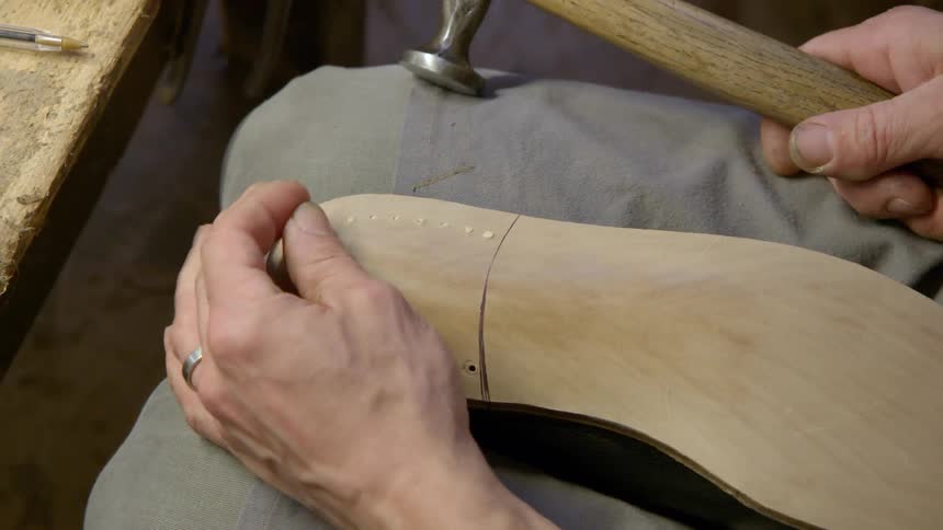 A shoemaker hammers a shoe together