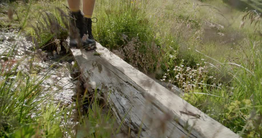 Someone is walking over a wooden blank across a small stream of water