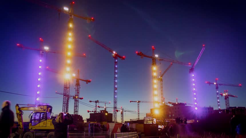 Large construction cranes spinning and lighting up at night
