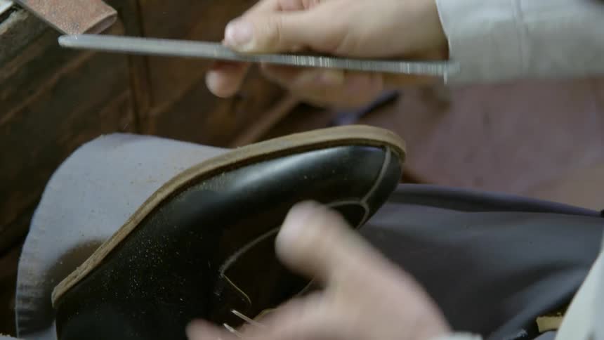 Person sands a shoe sole with a file