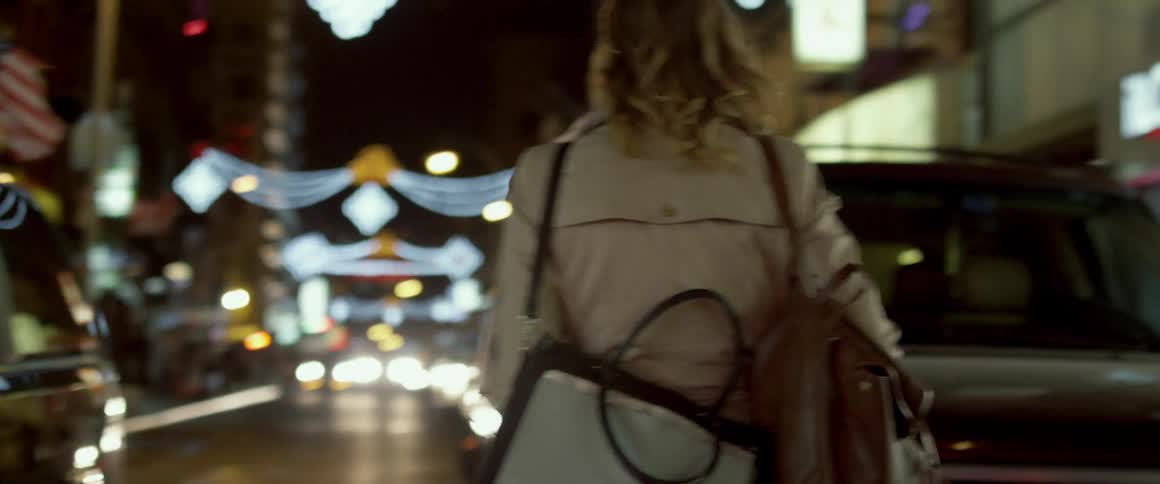 A woman is walking in traffic in a city at night