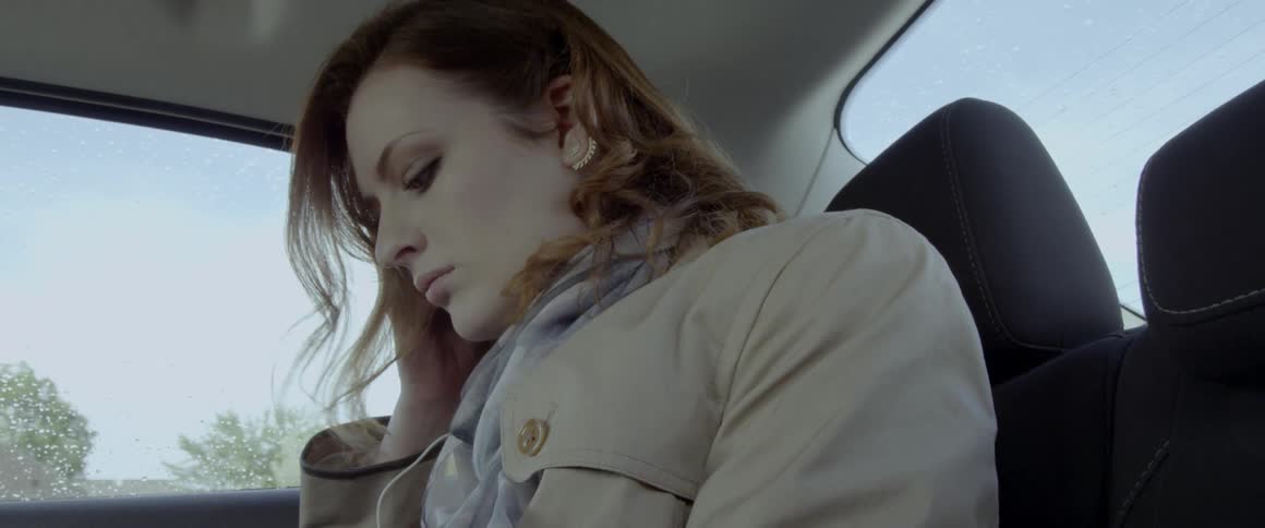 A woman is riding in the backseat of a car