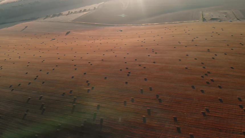 Hay bales are scattered across farm land