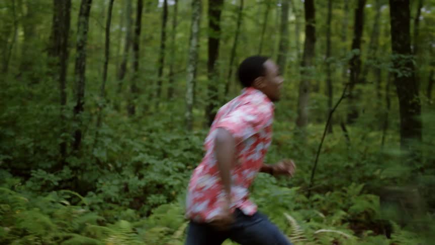 A man is running through a forest and calling out during the day