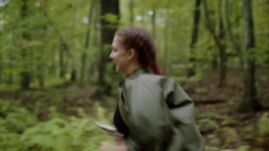 A young woman runs playfully in the woods