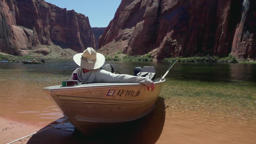 A man is lying in a boat that's between two large red mountains