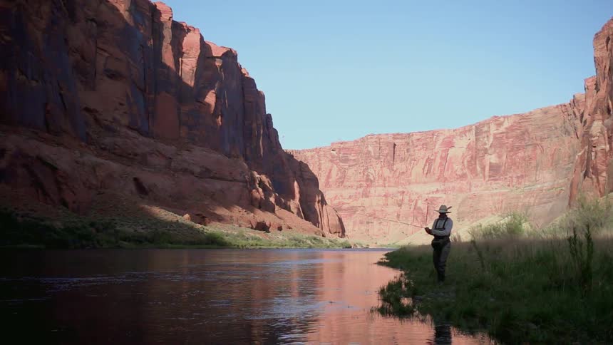 A man is finish in a river in a canyon