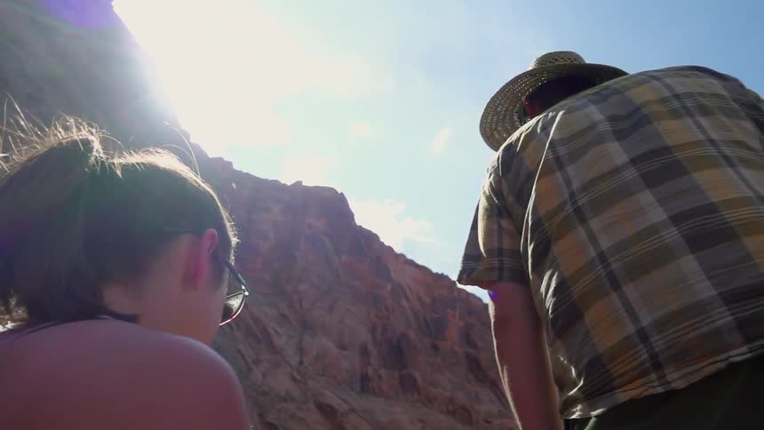 A man and young girl stand outside under the sun