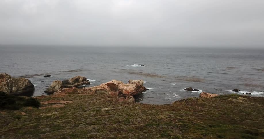 A green cliff side overlooks the ocean