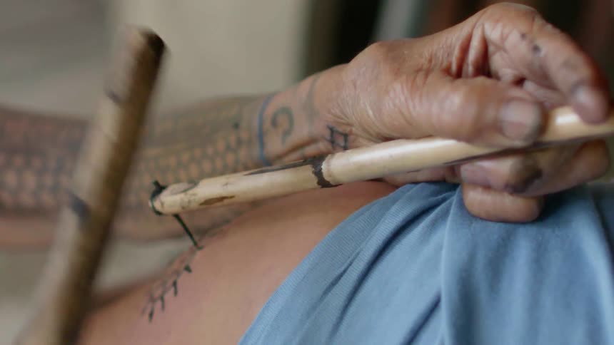 Someone is getting an old school tattoo with a nail and a stick