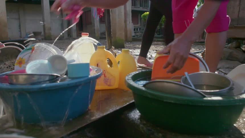 A person is washing dishes out in the yard