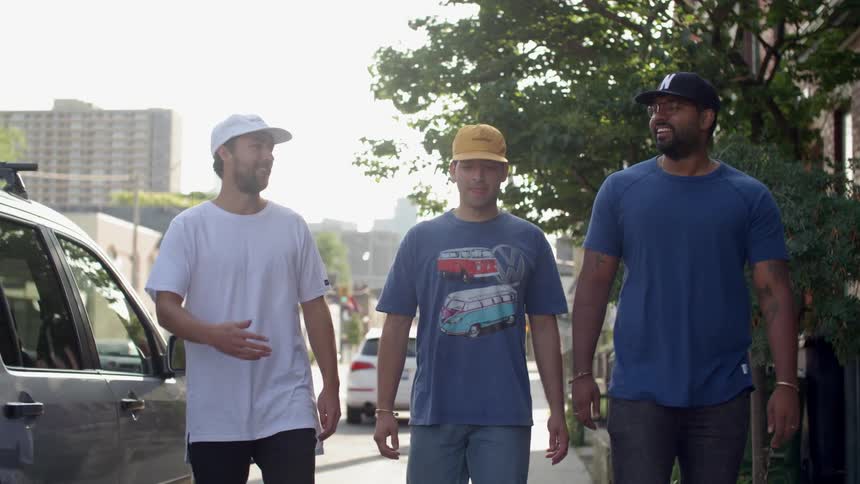 A group of men walk on a city sidewalk