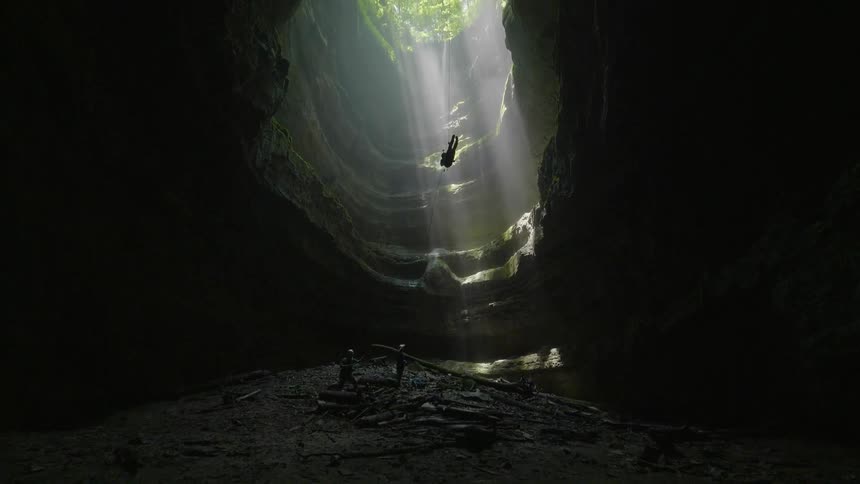 A cave diver descends into a cave with a harness