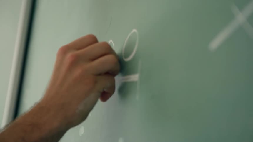 A teacher draws on the chalkboard
