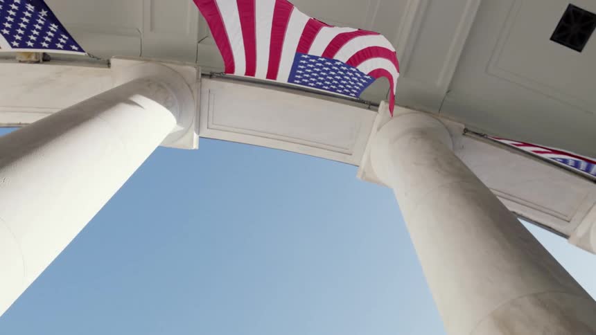 White pillars supporting a building with flag in between
