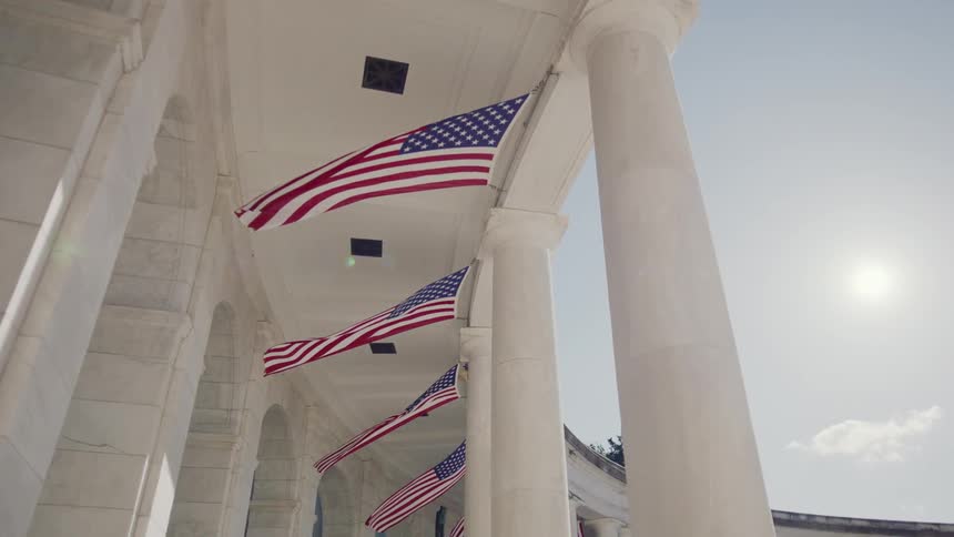American flags breeze in the wind at a monument